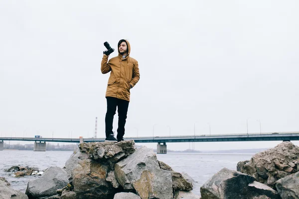 Photographer with camera on stone at river — Stock Photo, Image