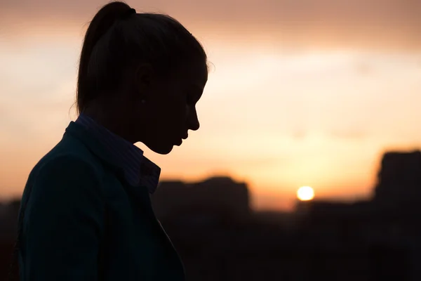 Жіночий силует над містом заходу сонця — стокове фото