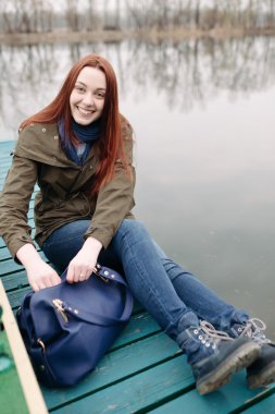 İskele üzerinde oturan genç kadın 