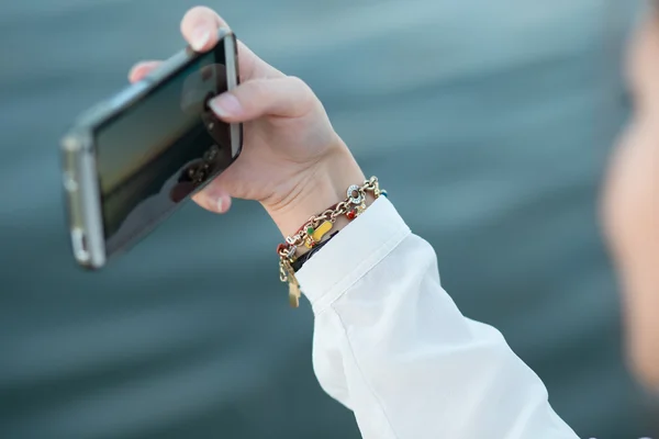 Flicka nära floden med smartphone — Stockfoto