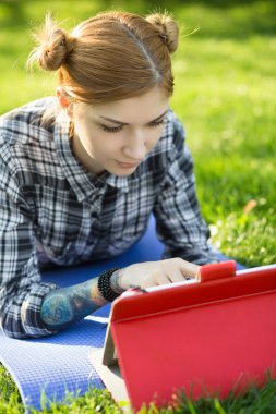 Genç kadın parkta onun dijital tablet kullanma