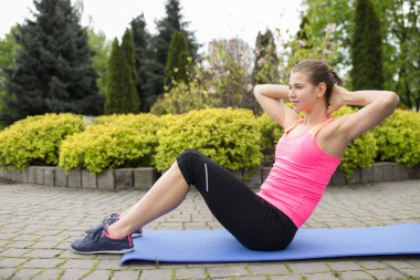 Genç kadın basın egzersizleri yaz gününde açık yapıyor