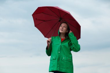 Yağmurluk bulutlu gökyüzü arka plan şemsiye tutan kadın