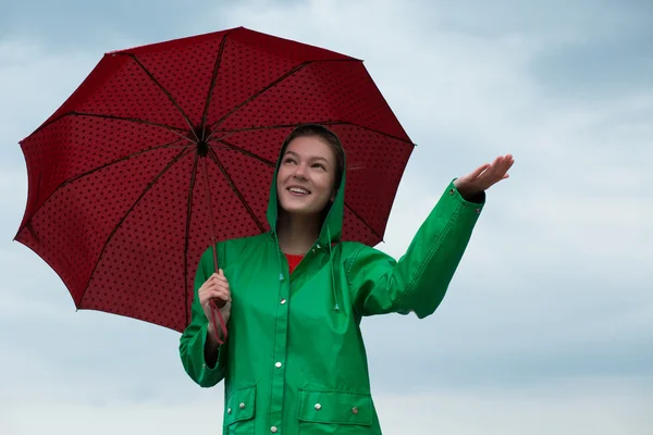 Mulher de capa de chuva segurando guarda-chuva no céu nublado fundo — Fotografia de Stock