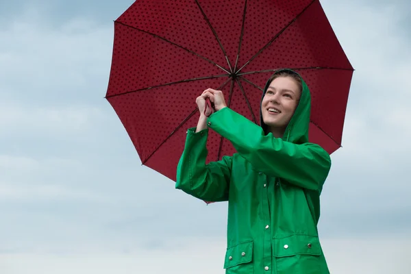 Mulher de capa de chuva segurando guarda-chuva no céu nublado fundo — Fotografia de Stock