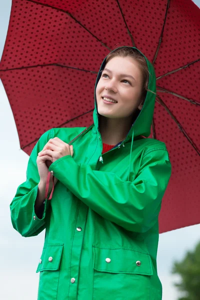 Mulher de capa de chuva segurando guarda-chuva no céu nublado fundo — Fotografia de Stock