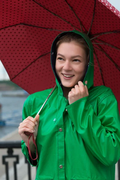 Kvinna i regnrock innehar paraply på staden vallen — Stockfoto