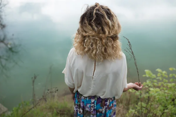 Cabelo encaracolado mulher de pé no lago, visão traseira — Fotografia de Stock
