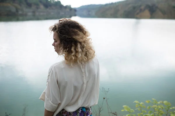 Gölde, arkadan görünüm duran kıvırcık saçlı kadın