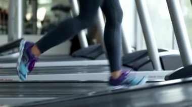Kadın fitness odasında bir koşu bandı üzerinde çalıştırın. Bacak yakın çekim