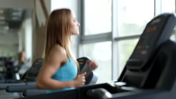 Jovem mulher em sala de fitness correr em uma esteira — Vídeo de Stock