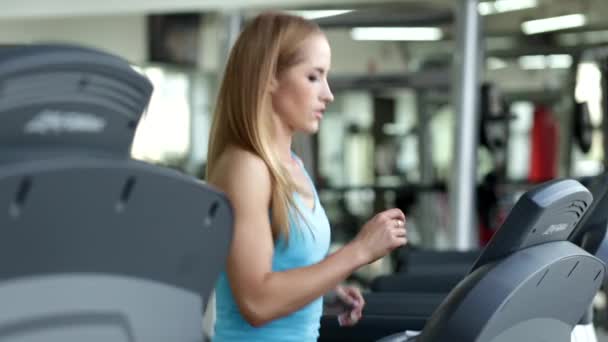 Jovem mulher em sala de fitness correr em uma esteira — Vídeo de Stock