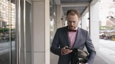 Cep telefonu üzerinde konuşurken ve bina yakın yürüme yetişkin iş adamı