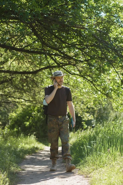 Homem turista caminhando na floresta na trilha e falar por celular — Fotografia de Stock