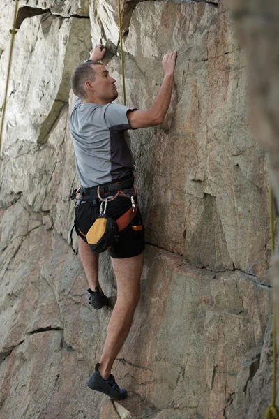 Masculino alpinista escalando uma estrutura de pedra — Fotografia de Stock