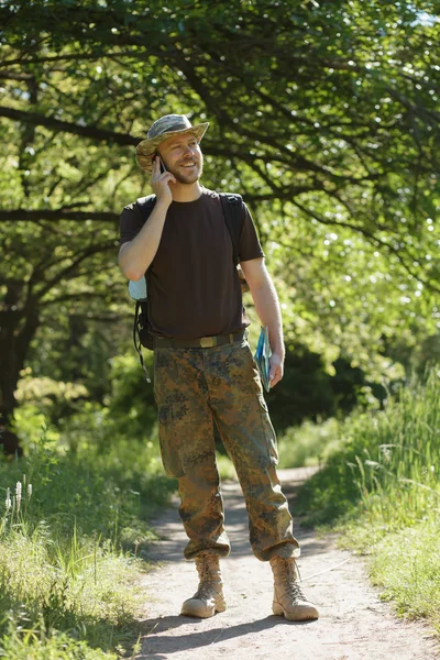 Homem turista caminhando na floresta na trilha e falar por celular — Fotografia de Stock