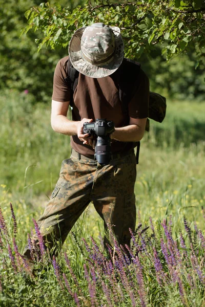 Fotógrafo disparando flores con cámara DSLR en el bosque —  Fotos de Stock