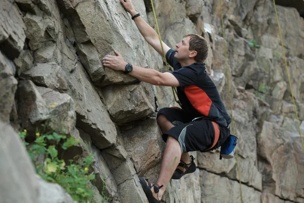 Masculino alpinista apega-se a um penhasco — Fotografia de Stock