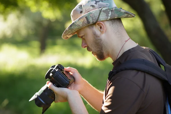Männlicher Tourist blickt auf seine DSLR-Kamera im Freien — Stockfoto