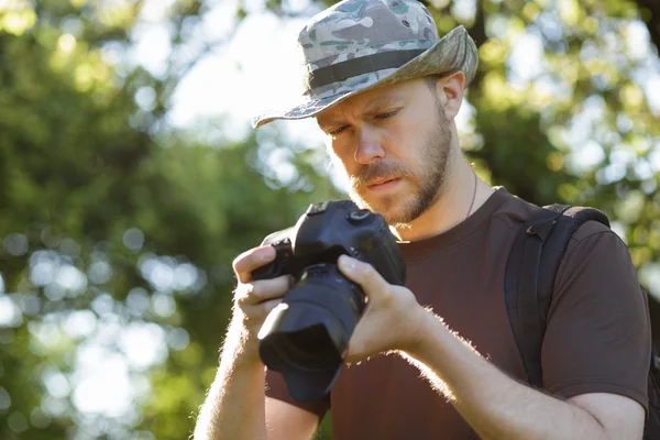 Männlicher Tourist blickt auf seine DSLR-Kamera im Freien — Stockfoto