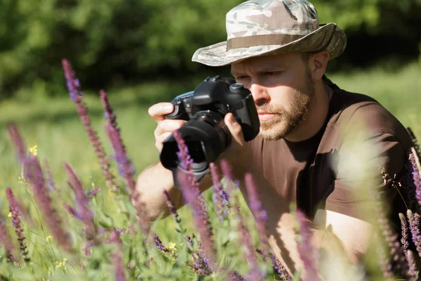 Fotógrafo fotografando flores com câmera DSLR na floresta — Fotografia de Stock