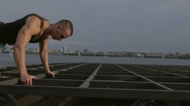 Nehirde metal yapılar üzerinde push up ile egzersiz adam