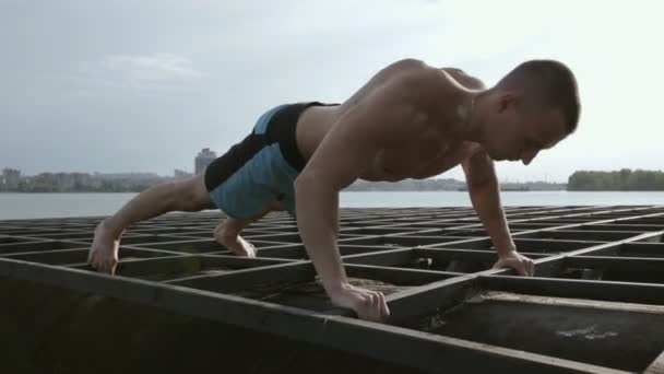 Człowieka, ćwiczenia z push up na konstrukcji metalowych, nad rzeką — Wideo stockowe