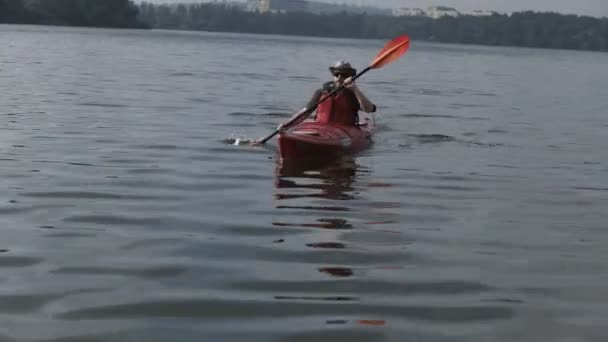 Человек на лодке в красном каноэ в реке в летний день — стоковое видео