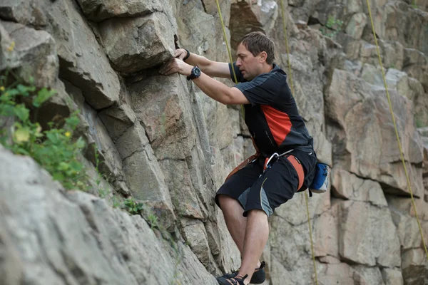 Masculino alpinista apega-se a um penhasco — Fotografia de Stock