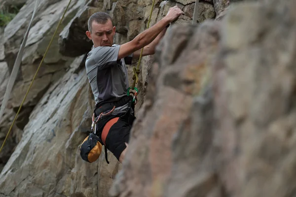 Masculino alpinista apega-se a um penhasco — Fotografia de Stock