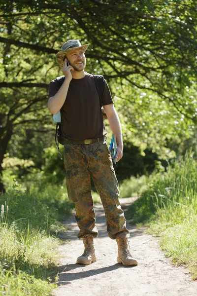 Männlicher Tourist läuft im Wald auf Wanderschaft und spricht per Handy — Stockfoto
