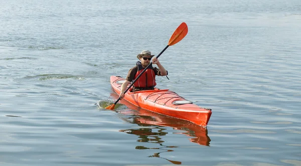 Man varen in rode kano in rivier op zomerdag — Stockfoto