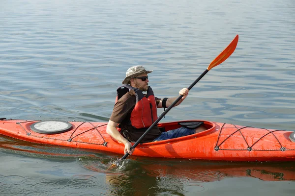 Man boating in red canoe in river at summer day