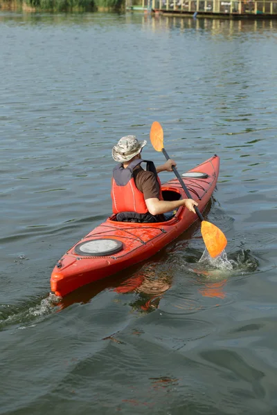 Mann fährt im roten Kanu im Fluss an Sommertagen, Rückseite — Stockfoto