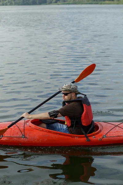 Man varen in rode kano in rivier op zomerdag — Stockfoto