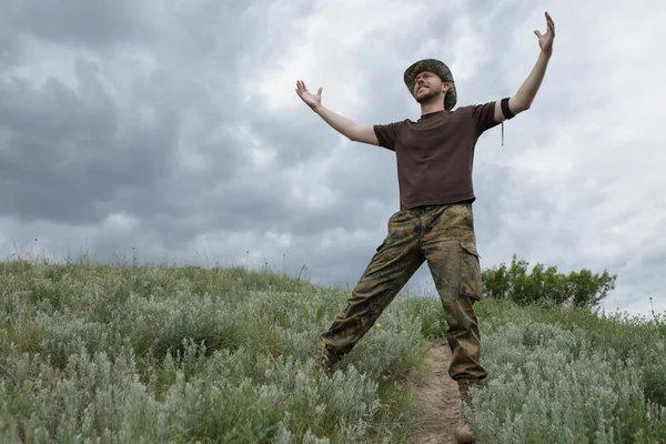 Человек свободы поднял руки в поле на мрачном фоне неба — стоковое фото