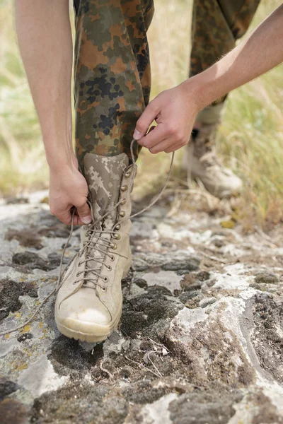 Ranger-Stiefel und Hände binden Schnürsenkel auf Stein — Stockfoto