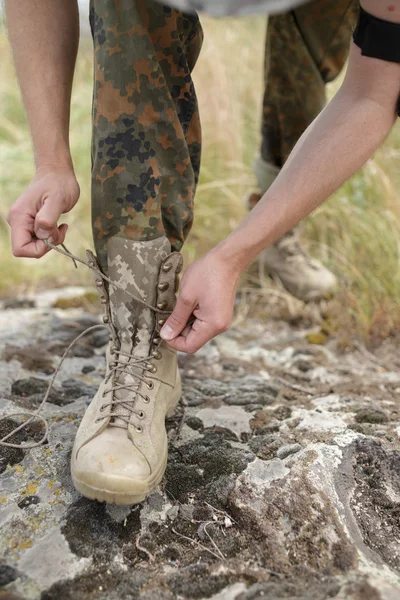 Ranger-Stiefel und Hände binden Schnürsenkel auf Stein — Stockfoto