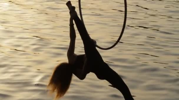 Silhouet van de vrouw doen sommige acrobatische elementen boven het water — Stockvideo