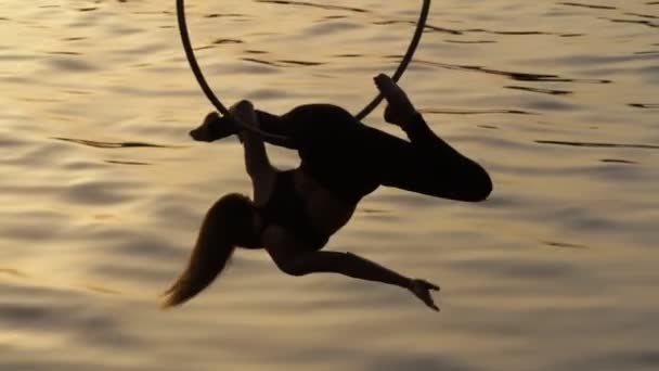 Silueta de mujer gimnasia de aire colgando sobre el agua — Vídeos de Stock