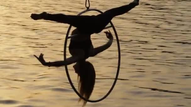 Silueta de gimnasia de aire mujer flexible que cuelga sobre el agua — Vídeos de Stock