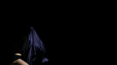 Kadın bir bez ile dans siyah arka plan ve Rüzgar esiyor