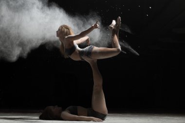 İki kadın akrobasi poz ve serpin un siyah arka plan üzerine