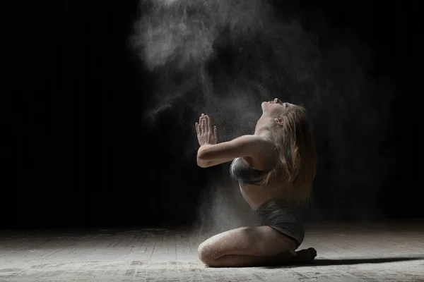 Balerina sentado y espolvorear harina sobre fondo negro — Foto de Stock