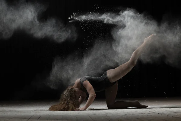 Mujer flexible bailando y espolvorear harina sobre fondo negro —  Fotos de Stock