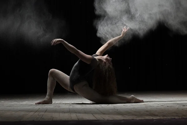 Mujer flexible bailando con harina sobre fondo negro — Foto de Stock