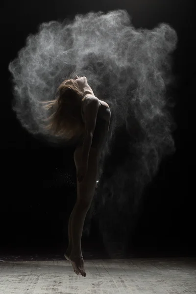 Flexibel kvinna hoppa och strö mjöl på svart bakgrund — Stockfoto