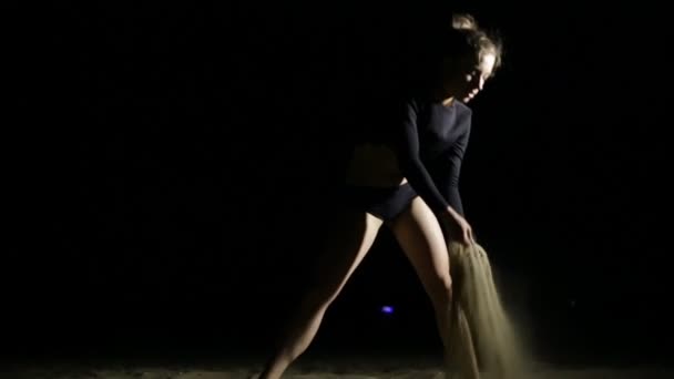 Graziosamente giovane donna versando sabbia di notte spiaggia, sfondo nero — Video Stock