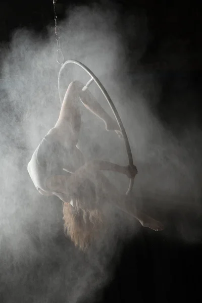 Akrobatiska kvinna gör gymnastiska inslag på aerial hoop med beströdda mjöl — Stockfoto