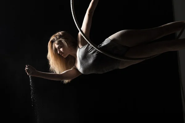 Acrobatic woman hunging on aerial hoop and pouring flour — Stock Photo, Image